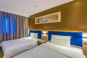 A hotel room with two beds, a bedside table with a phone, and a painting on the wall. - 7 Days Premium (Beijing)