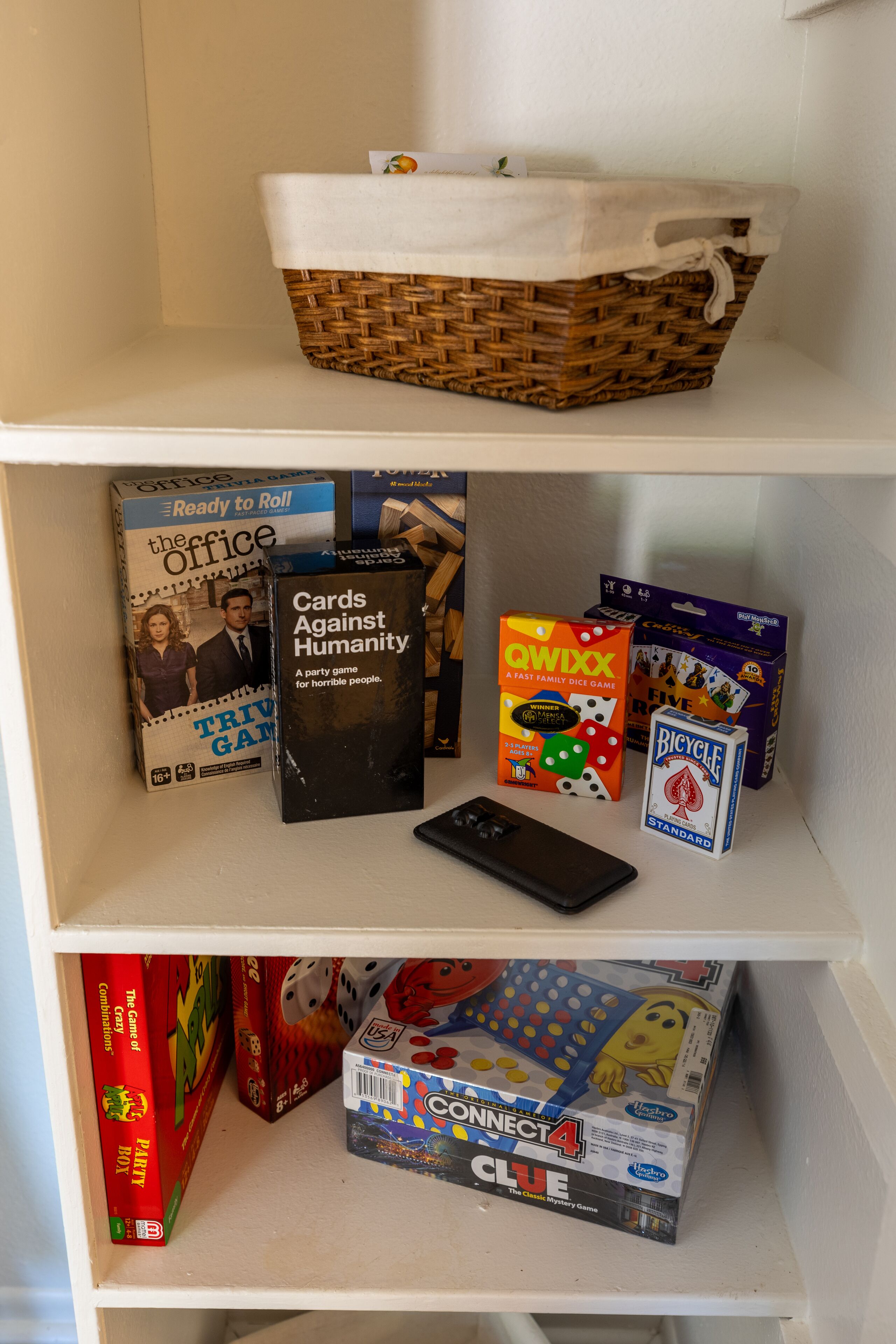 Una estantería con varios juegos de mesa y un control remoto.