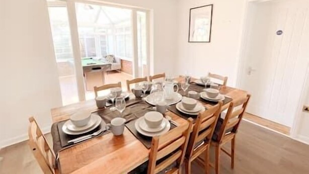 Un coin repas avec une table en bois dressée pour six personnes, entourée de chaises en bois.
