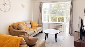 Un salon avec un canapé, une table basse et un téléviseur.