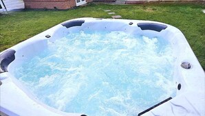 Un bain à remous de forme rectangulaire, entouré d’une zone herbeuse.