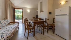 A compact living space with a sofa, dining table, chairs, a refrigerator, and a kitchen area. - Apartment in Giannella with 2 bedrooms sleeps 4 (Giannella)