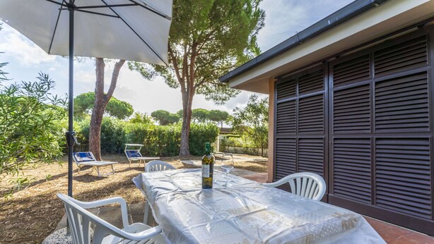 An outdoor dining area with a table set for two, surrounded by white chairs, under a large umbrella. - Apartment in Giannella with 2 bedrooms sleeps 4 (Giannella)