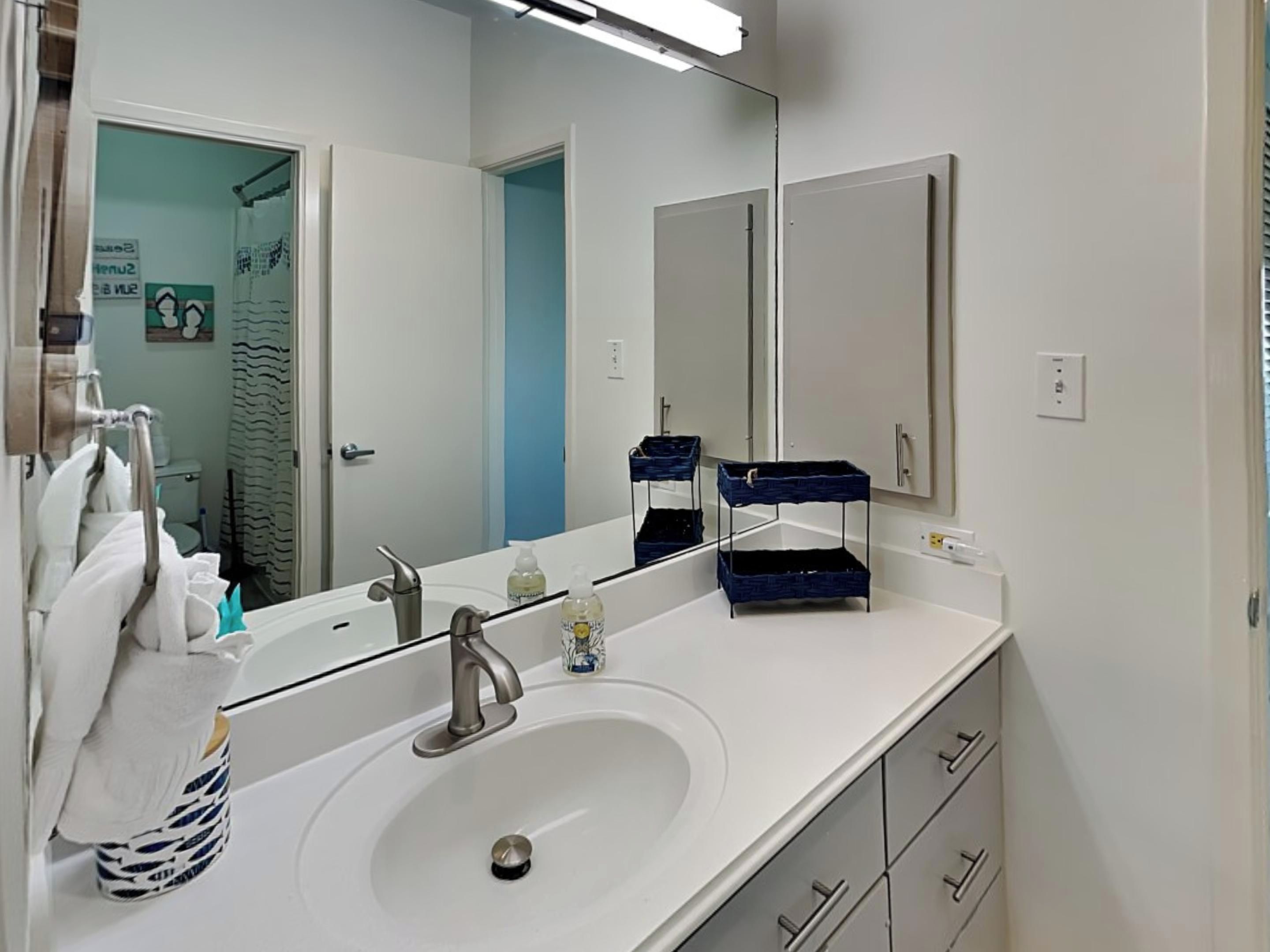 Un baño moderno con un lavamanos blanco, un espejo y un perchero para toallas.