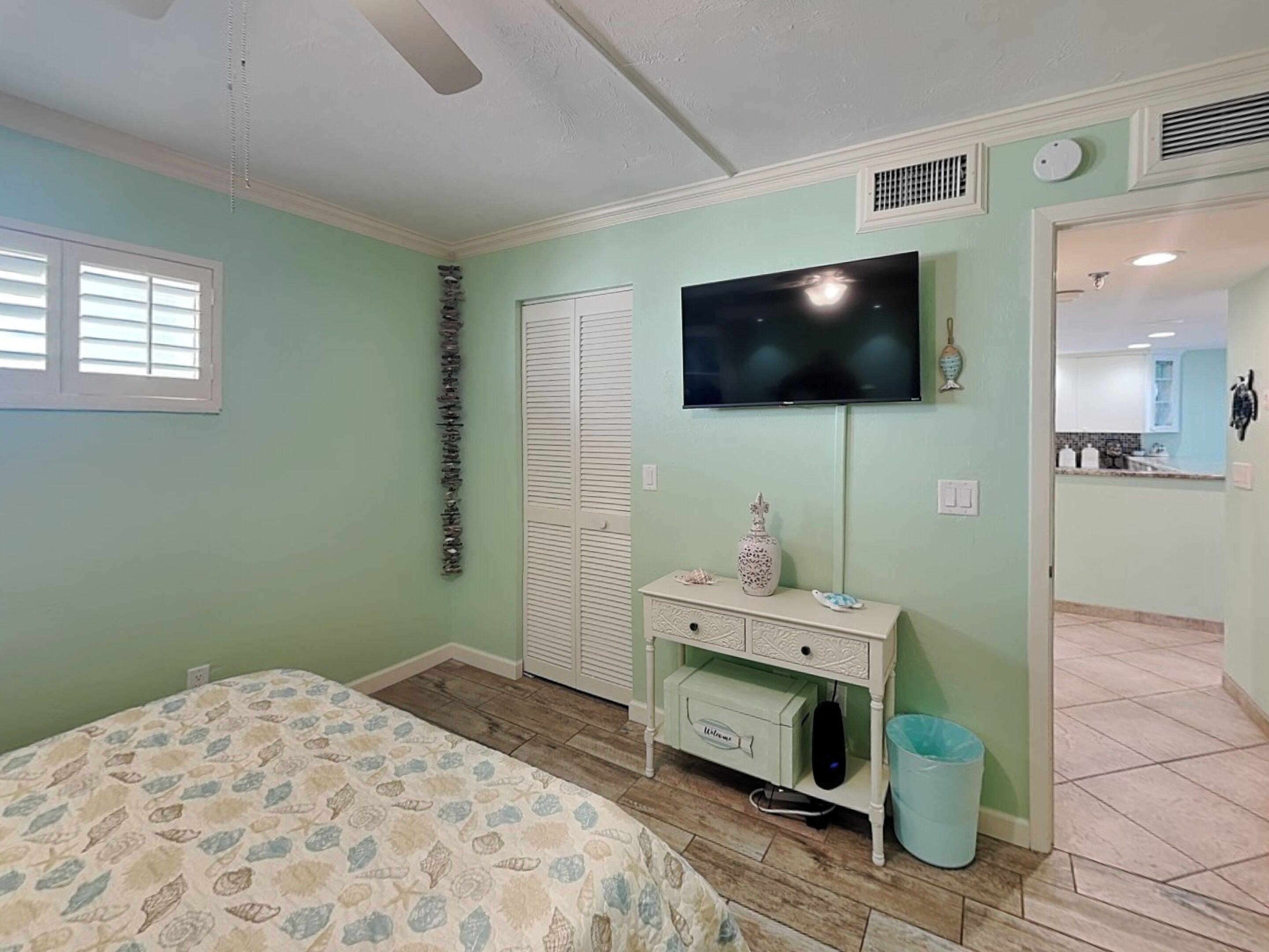 Un dormitorio con cama, cómoda, televisor y baño visible a través de una puerta abierta.