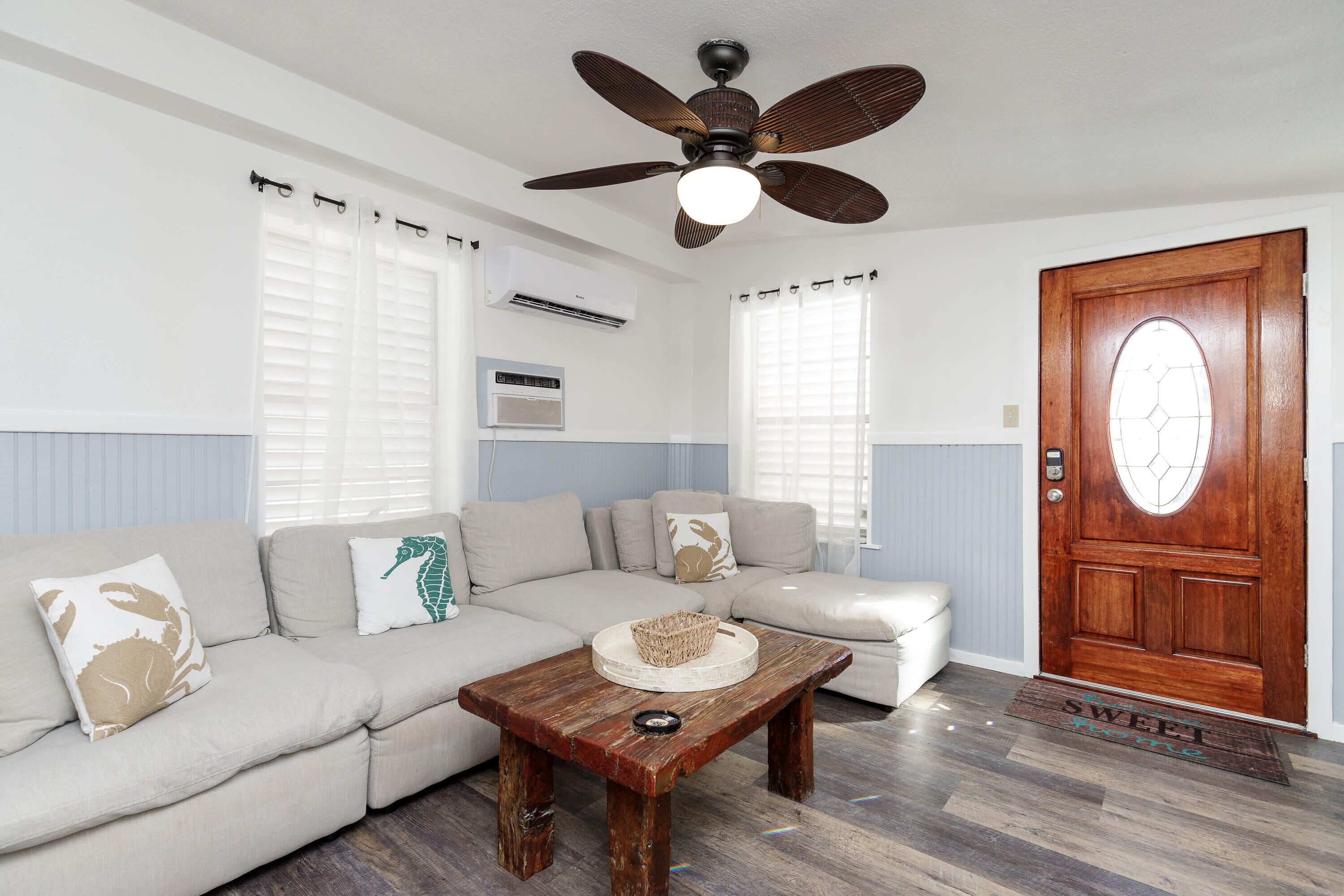 A living room with a wooden coffee table, beige sofa, and a ceiling fan.
