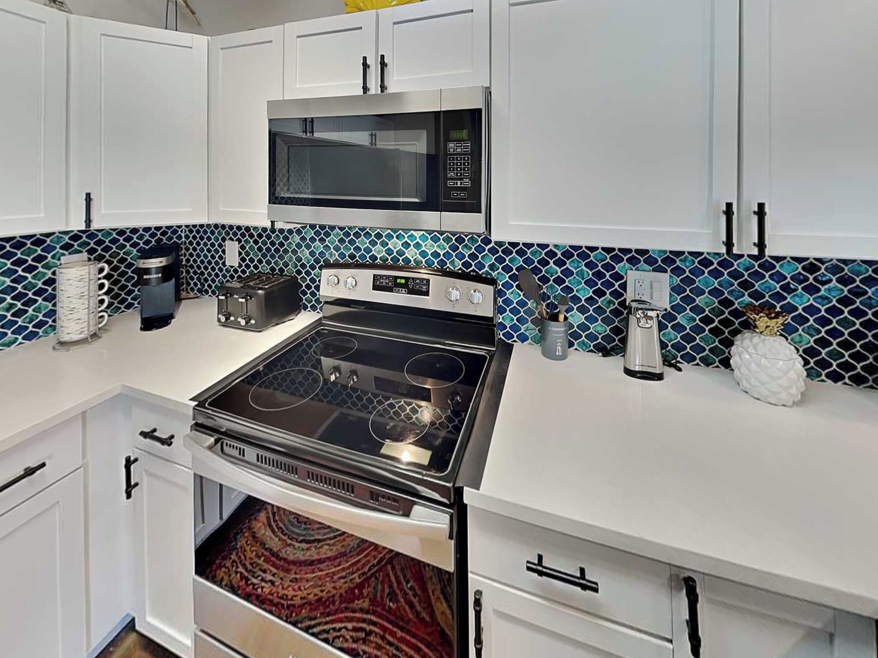A kitchen with white cabinets, a microwave, a stove, and a toaster.