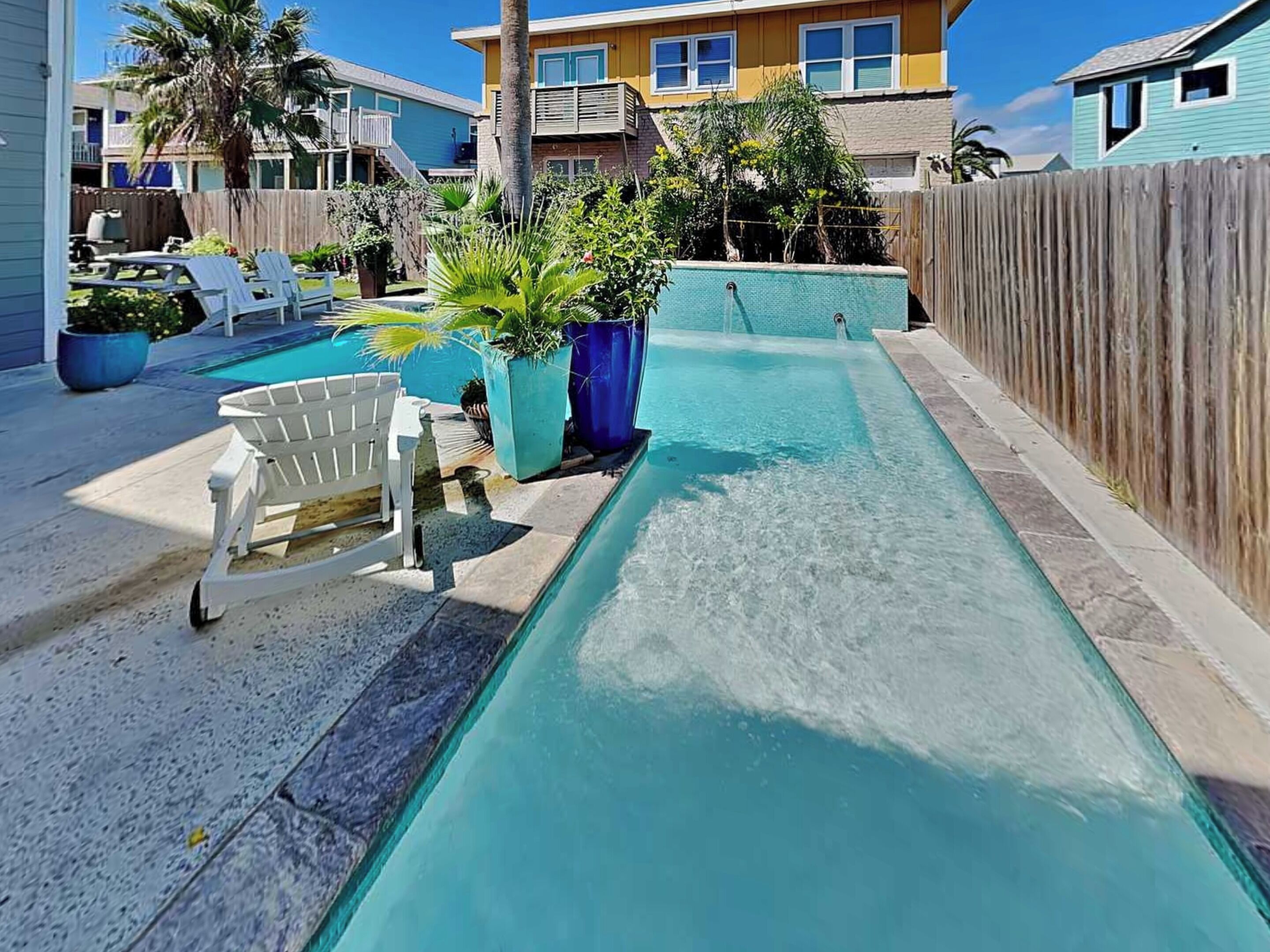 A swimming pool with lounge chairs and potted plants.