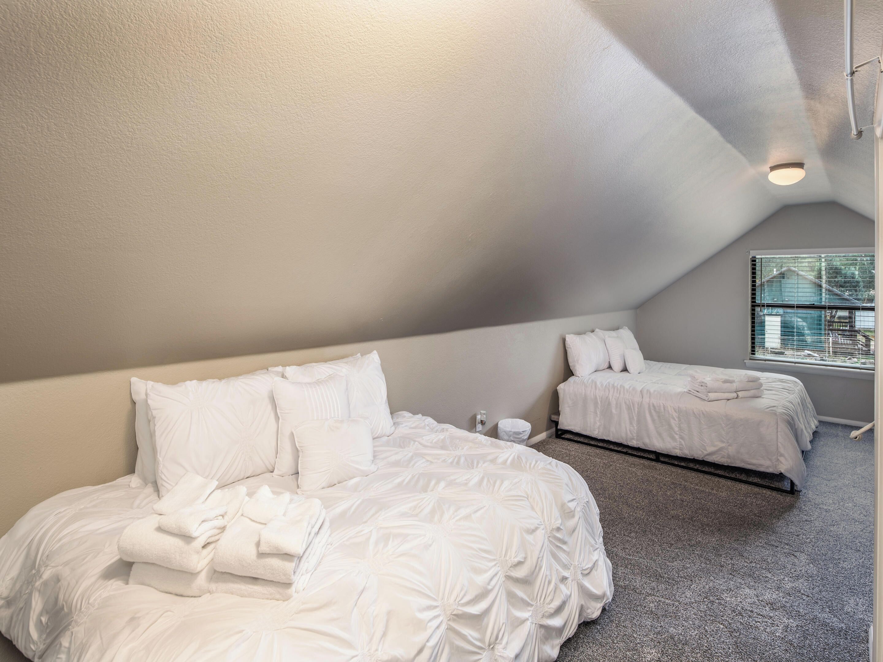 A bedroom with two beds, a window, and a ceiling light.