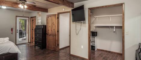 Un dormitorio con techo de madera, una cama, un aparador, un armario, un televisor y un closet.