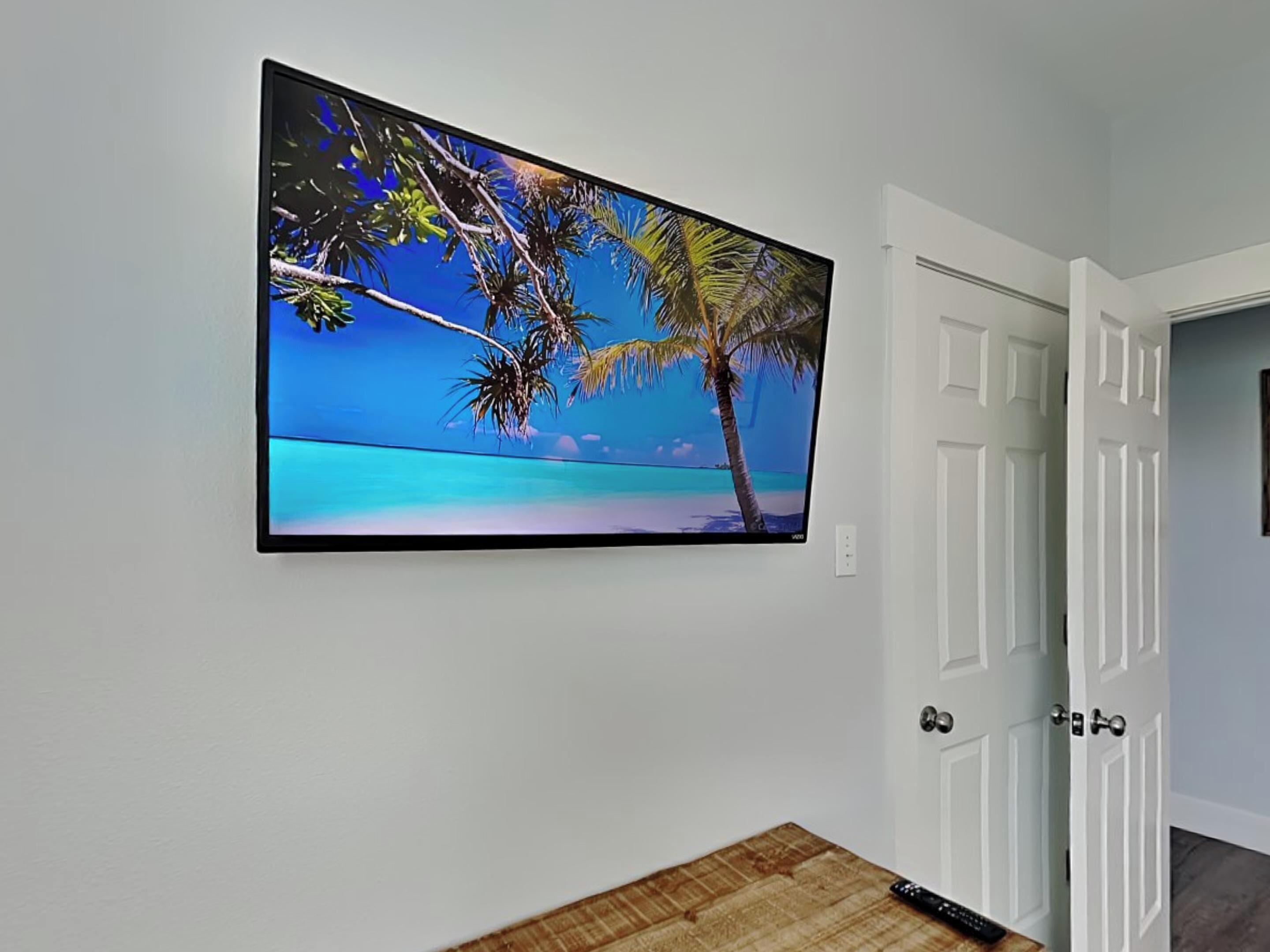 A flat-screen TV mounted on a wall displaying a tropical beach scene.