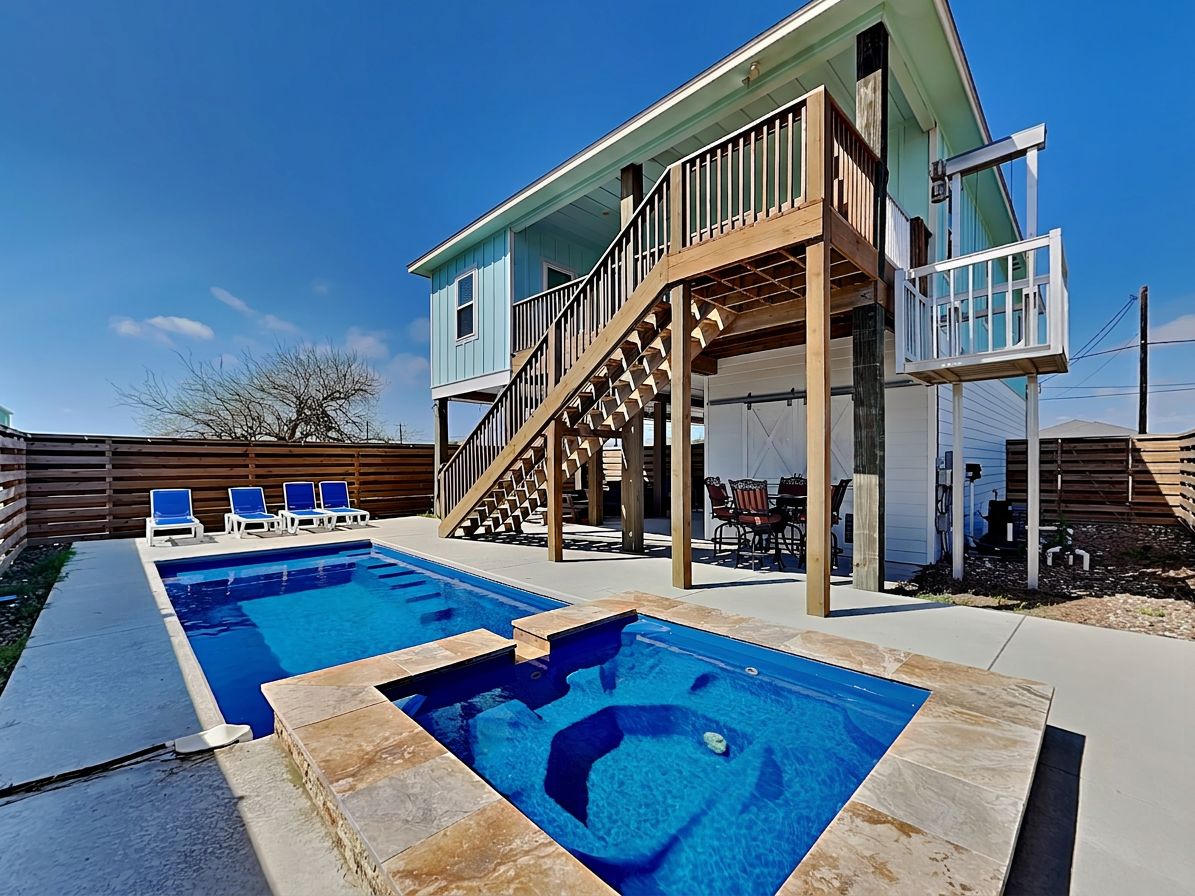 Et toetagers hus med swimmingpool, udendørs siddepladser og en trappe til en terrasse.