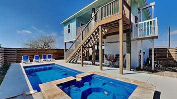 Une maison à deux étages dotée d’une piscine, d’un espace salon extérieur et d’un escalier menant à une terrasse.