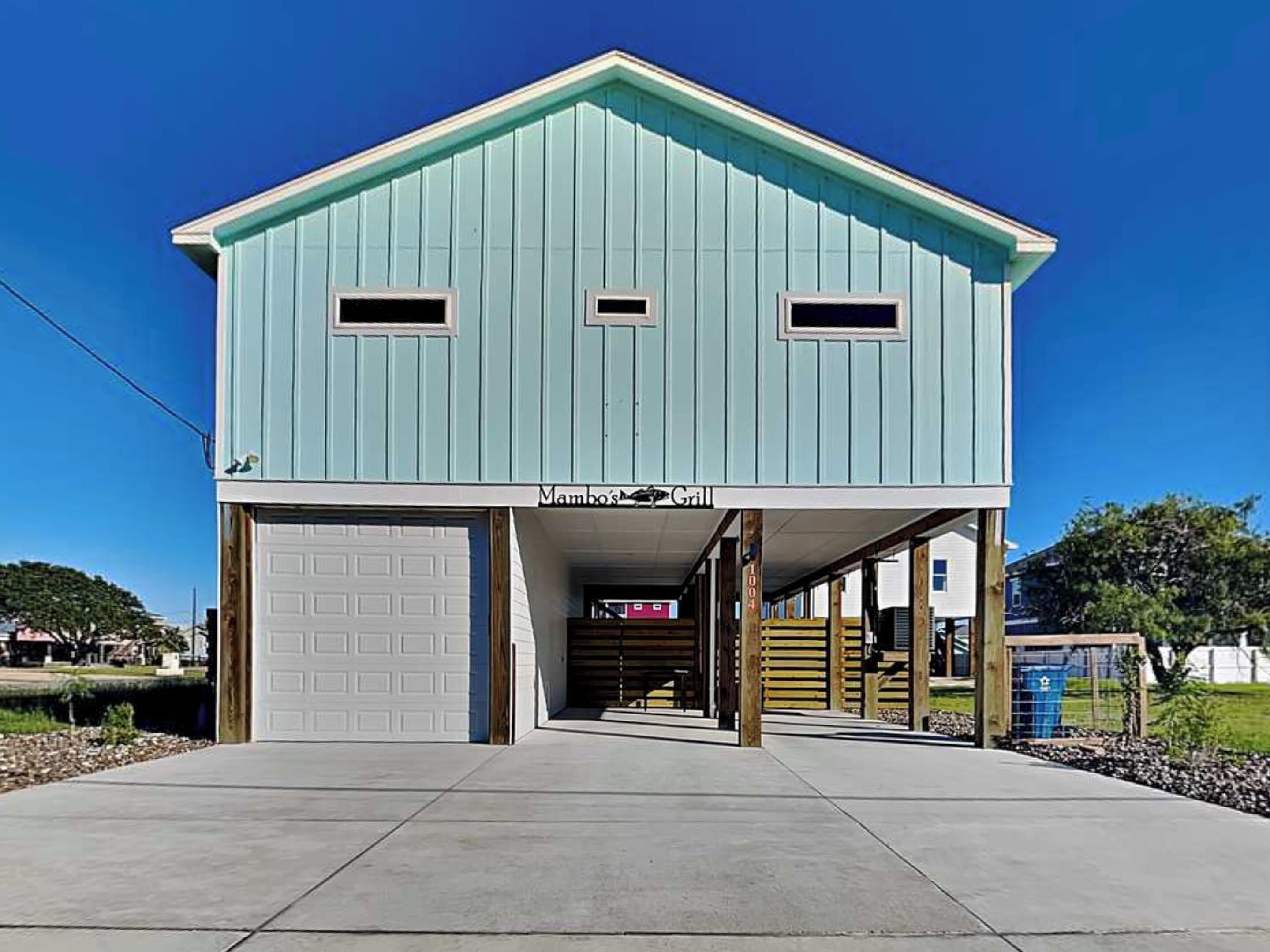 A light blue building with a garage, a covered entrance, and a sign reading 'Mambo's Grill'.