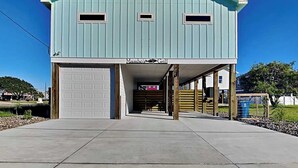 A light blue building with a garage, a covered entrance, and a sign reading 'Mambo's Grill'. - Mambo's Grill by Miss Kitty’s (Rockport)