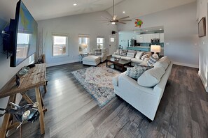 A spacious living room with a grey sofa, a wooden coffee table, and a large rug. - Mambo's Grill by Miss Kitty’s (Rockport)