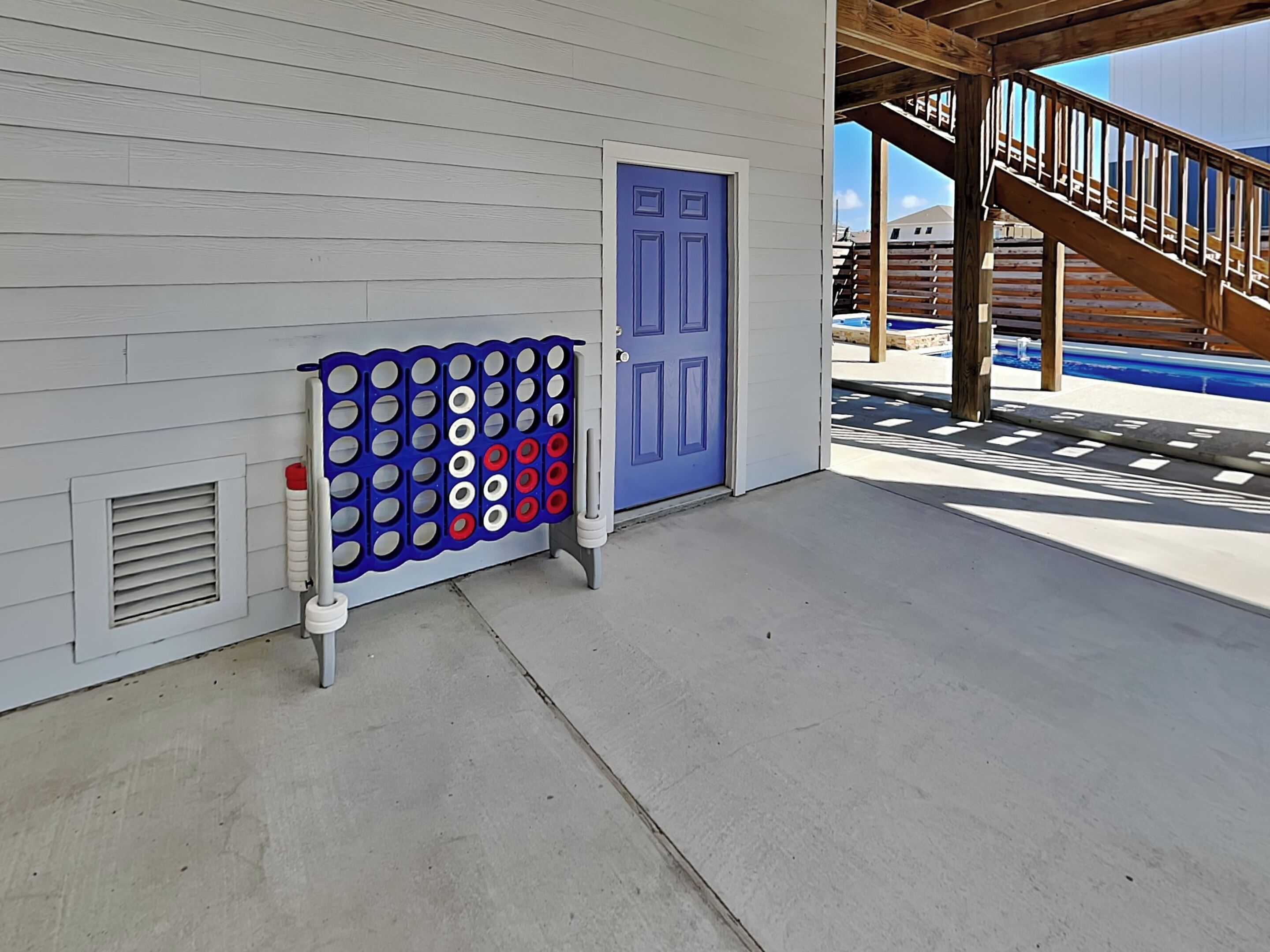 A pool area with a blue door, a wooden staircase, and a pool ladder.