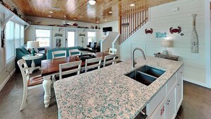 Una cucina moderna con un piano di lavoro in granito, lavello incassato e zona pranzo con tavolo e sedie in legno.