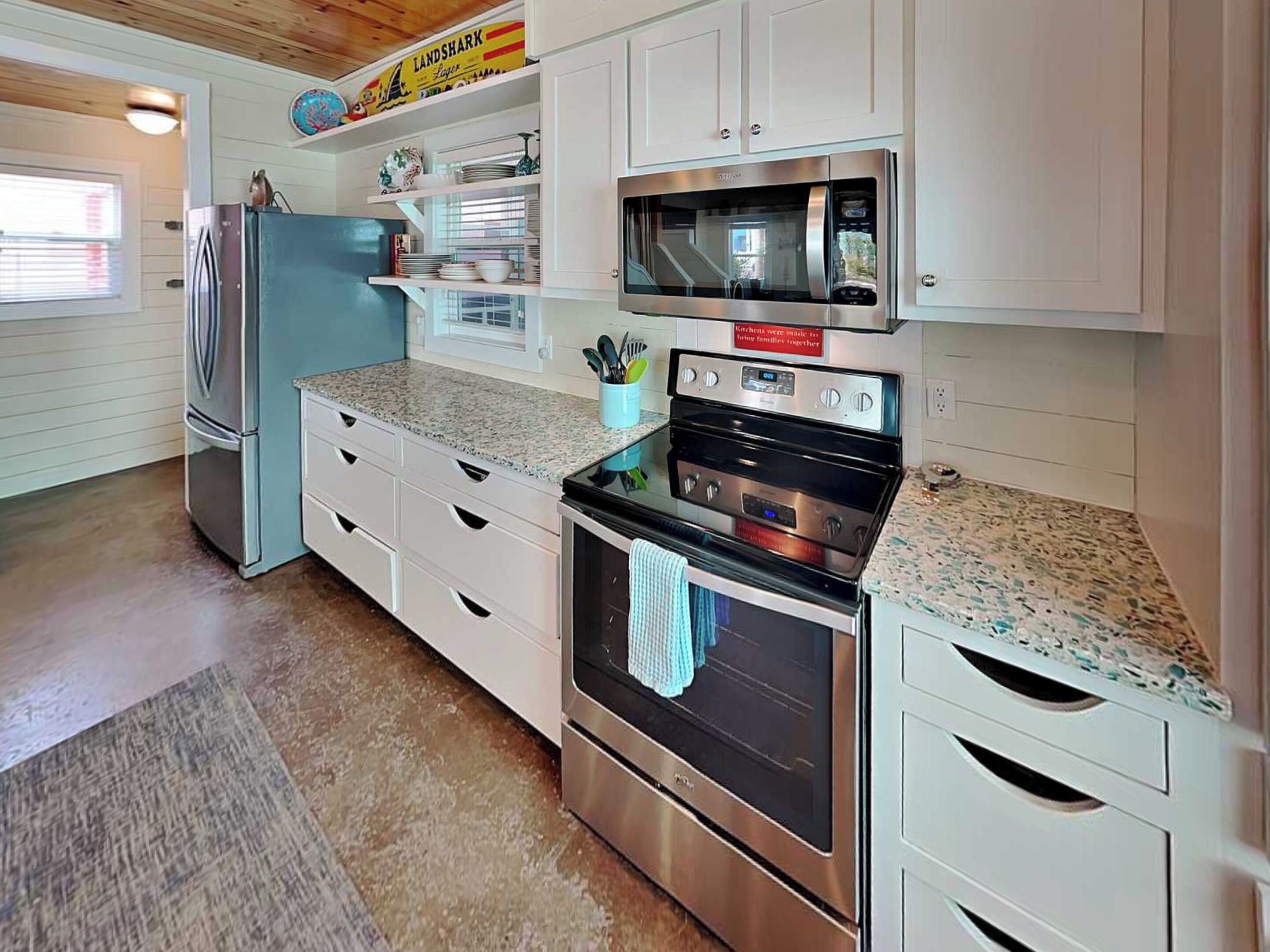 A kitchen with white cabinetry, a stainless steel refrigerator, a microwave, and an oven.