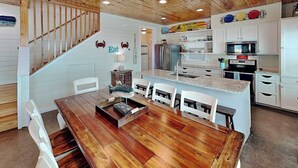 Una cucina moderna con mobili bianchi, un tavolo da pranzo in legno e un'isola integrata con forno a microonde e forno.