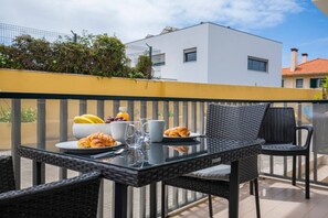 A balcony with a table set for breakfast, including croissants, fruit, and a glass of juice.