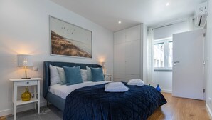 Ein Schlafzimmer mit einem großen Bett, einem Nachttisch mit Lampe, einem Bild an der Wand und einem Kleiderschrank.