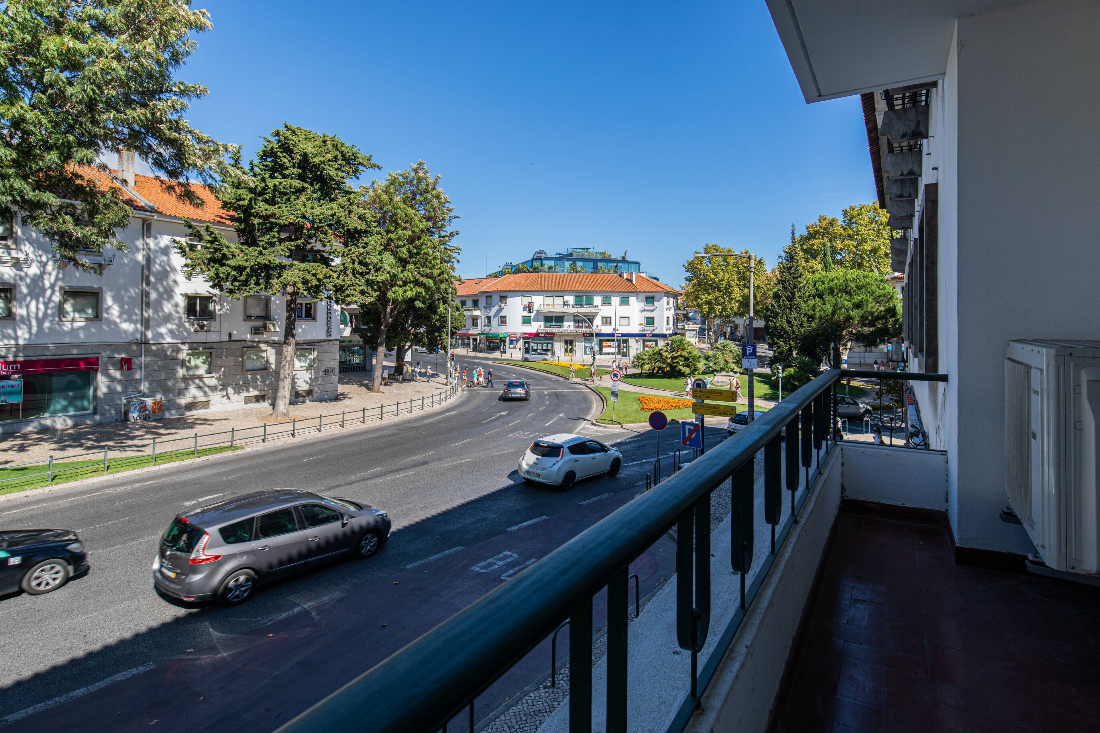 Ein Balkon mit Blick auf eine Straße, an der Autos, Gebäude und Bäume zu sehen sind.