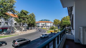 Ein Balkon mit Blick auf eine Straße, an der Autos, Gebäude und Bäume zu sehen sind.