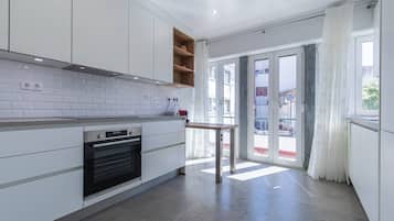 Eine moderne Küche mit weißen Schränken, einem eingebauten Backofen und einem kleinen Tisch.