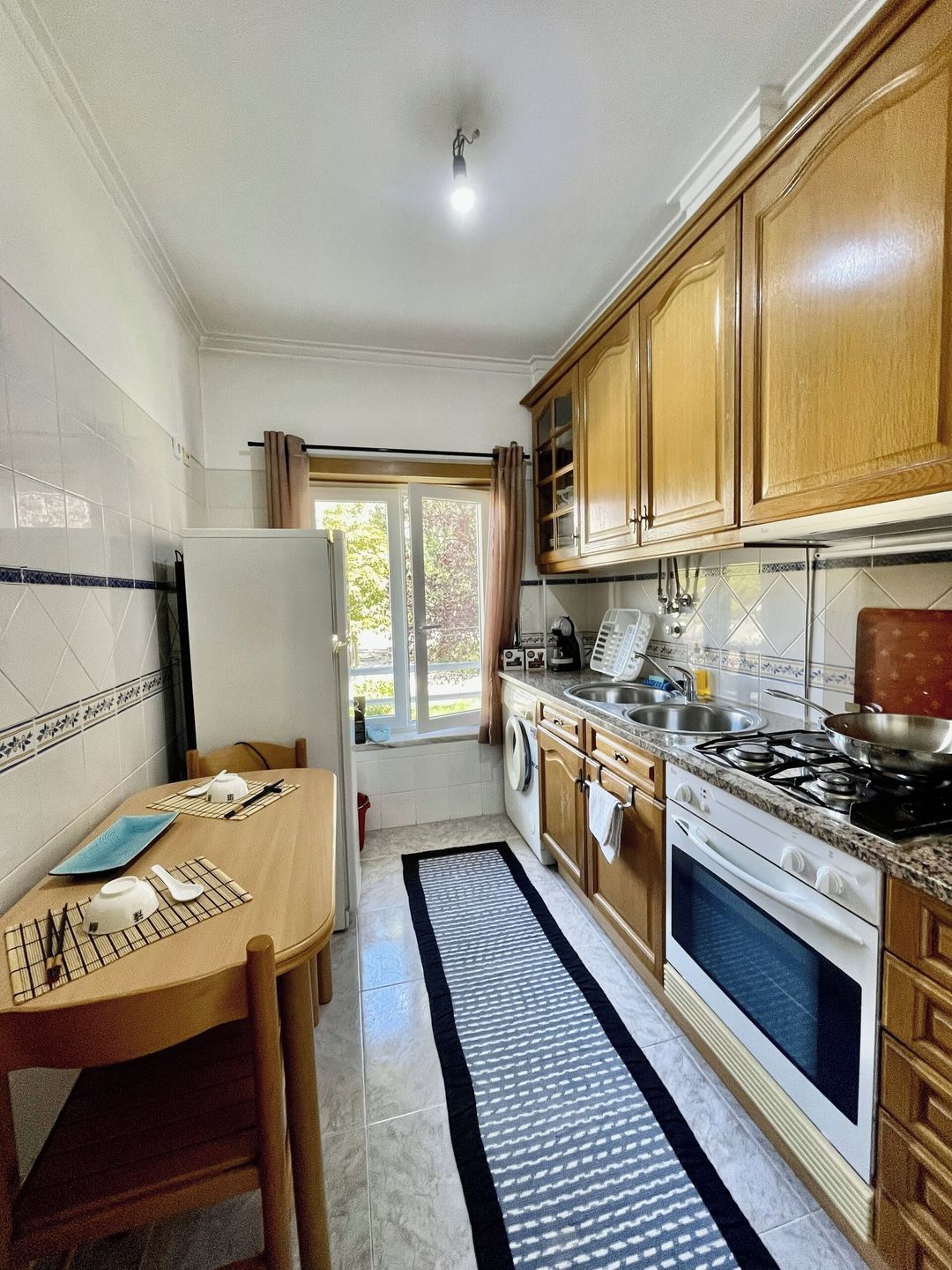 A compact kitchen with a dining table, a stove, and a washing machine.