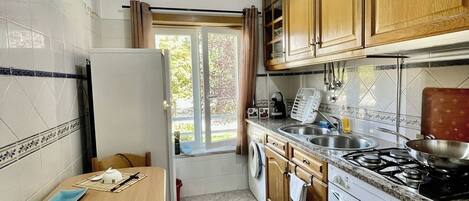 A compact kitchen with a dining table, a stove, and a washing machine.