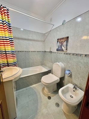 Une salle de bain comprenant des toilettes, un bidet, un lavabo et une baignoire.