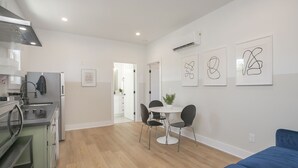 A modern kitchen with a built-in oven, a dining area with a round table and chairs, and a blue sofa.