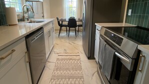 Une cuisine moderne avec des meubles blancs, un réfrigérateur en acier inoxydable et un coin repas comprenant une table et des chaises.