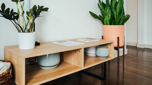 Une console en bois ornée de deux plantes en pot, d’une tasse blanche et d’un petit panier.