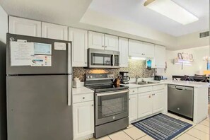 Uma cozinha moderna com armários brancos, eletrodomésticos de aço inoxidável e painel de azulejos.