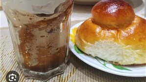 Un verre de café glacé, surmonté de crème fouettée, et une assiette avec un pain glacé.