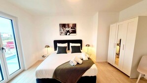 A modern bedroom with a large bed, a wardrobe, and a view of the outside. - Spacious & Luxurious 5 bedrooms House (Reckange-sur-Mess)