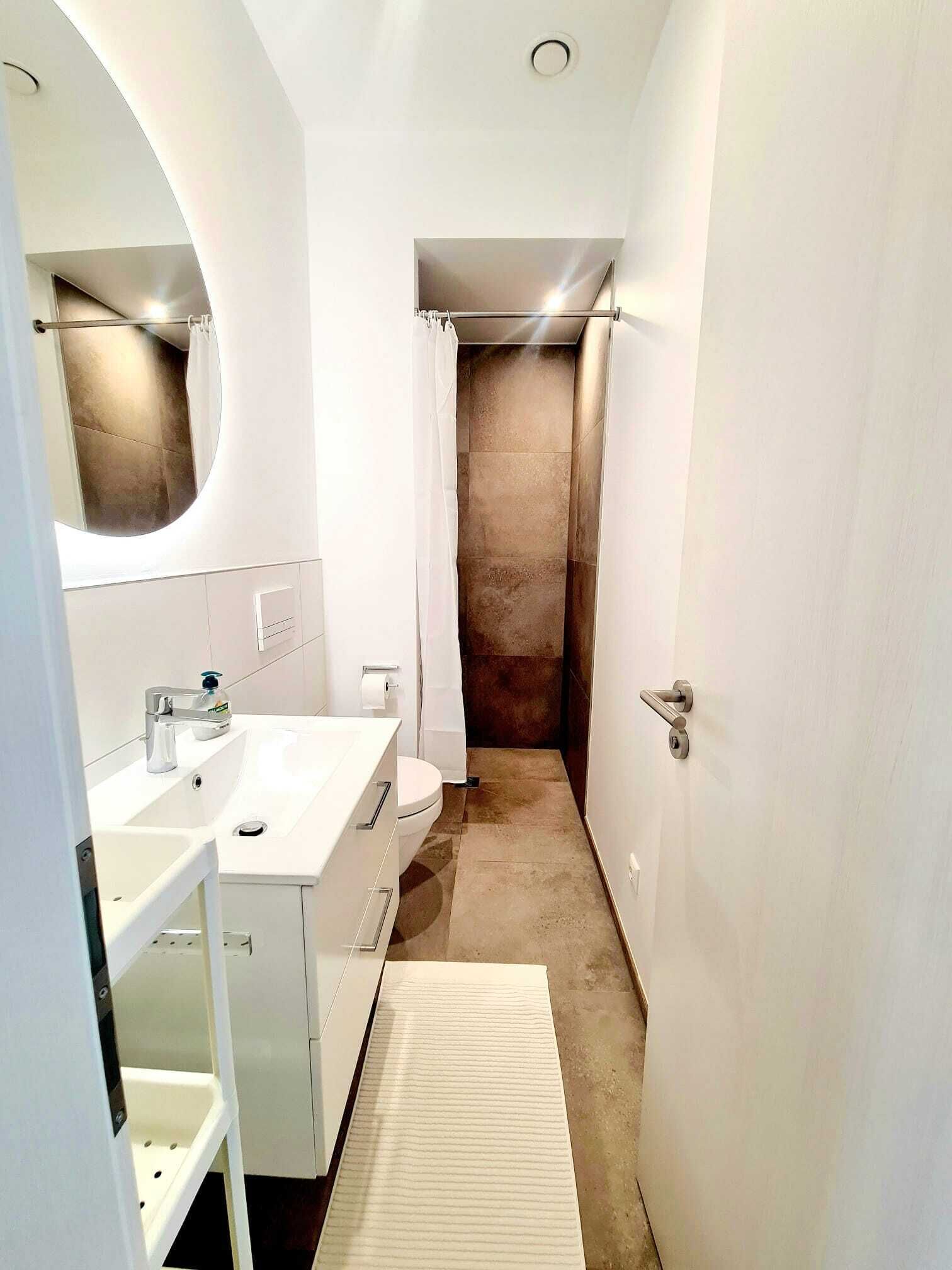 A modern bathroom with a white vanity, a toilet, and a shower area.
