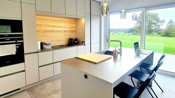 A modern kitchen with a central island, built-in appliances, and large windows offering a view of the outdoors. - Spacious & Luxurious 5 bedrooms House (Reckange-sur-Mess)