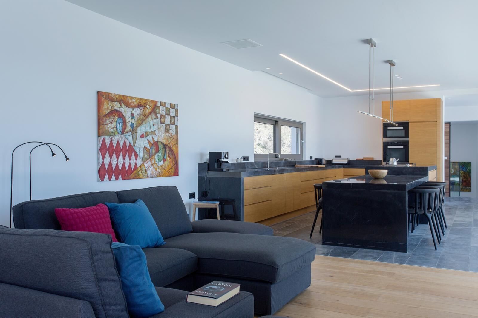 A modern living room with a grey sofa, a coffee table, and a bookshelf.