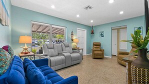 Ein Wohnzimmer mit einem blauen Sofa, einem grauen Liegesessel und einem braunen Sessel. Auf Beistelltischen stehen zwei Lampen, eine Meerstern-Dekoration und eine Pflanze.