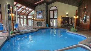 Una piscina interior con pared de piedra, un mural y sillones de descanso.