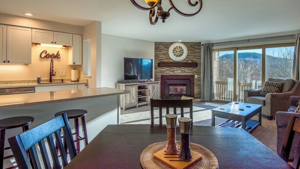 Una cocina moderna con un cartel que dice 'Cook', un comedor con chimenea y vistas al exterior.