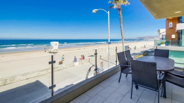 A balcony with a view of the beach, a palm tree, and outdoor seating. - Surf View-2 Decks with Ocean views, Garage (San Diego)
