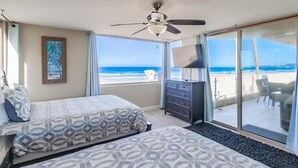 A hotel room with two beds, a ceiling fan, a large window with a view of the beach, and a sliding glass door leading to an outdoor area. - Surf View-2 Decks with Ocean views, Garage (San Diego)