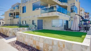 A modern multi-story building with balconies, a swimming pool, and a well-maintained lawn. - Surf View-2 Decks with Ocean views, Garage (San Diego)