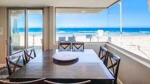 A dining area with a large table and chairs, a view of the beach, and a clear sky. - Surf View-2 Decks with Ocean views, Garage (San Diego)