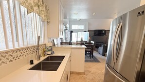 Una cocina con un refrigerador de acero inoxidable, un lavamanos y una zona de comedor con una mesa y sillas.