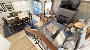 Un salón espacioso con chimenea, un comedor y una escalera que lleva a un nivel superior.